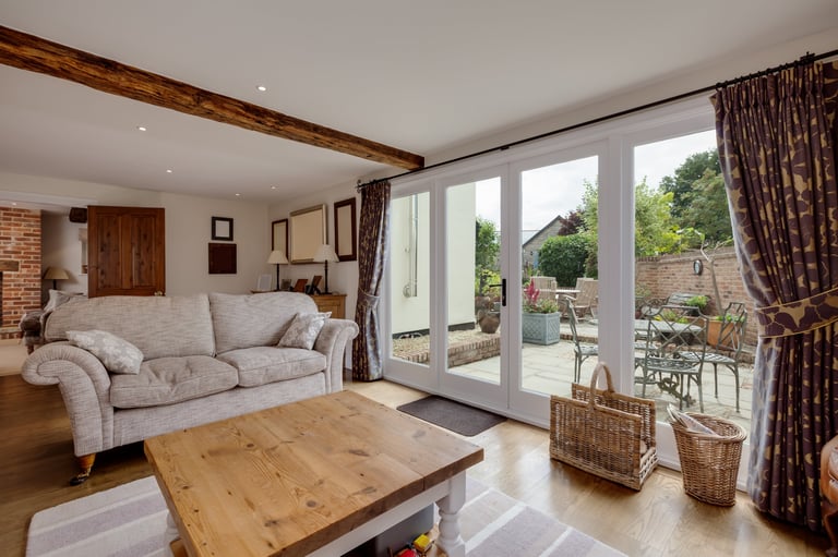 Modern living room with aluminium bifold stacking doors leading to a patio and garden