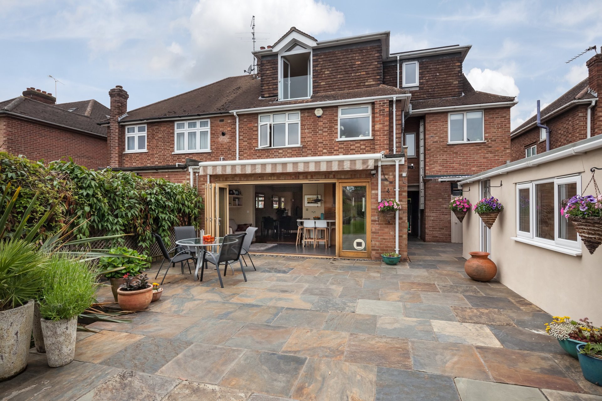 Aluminium bifold stacking doors opened wide onto a landscaped patio and garden