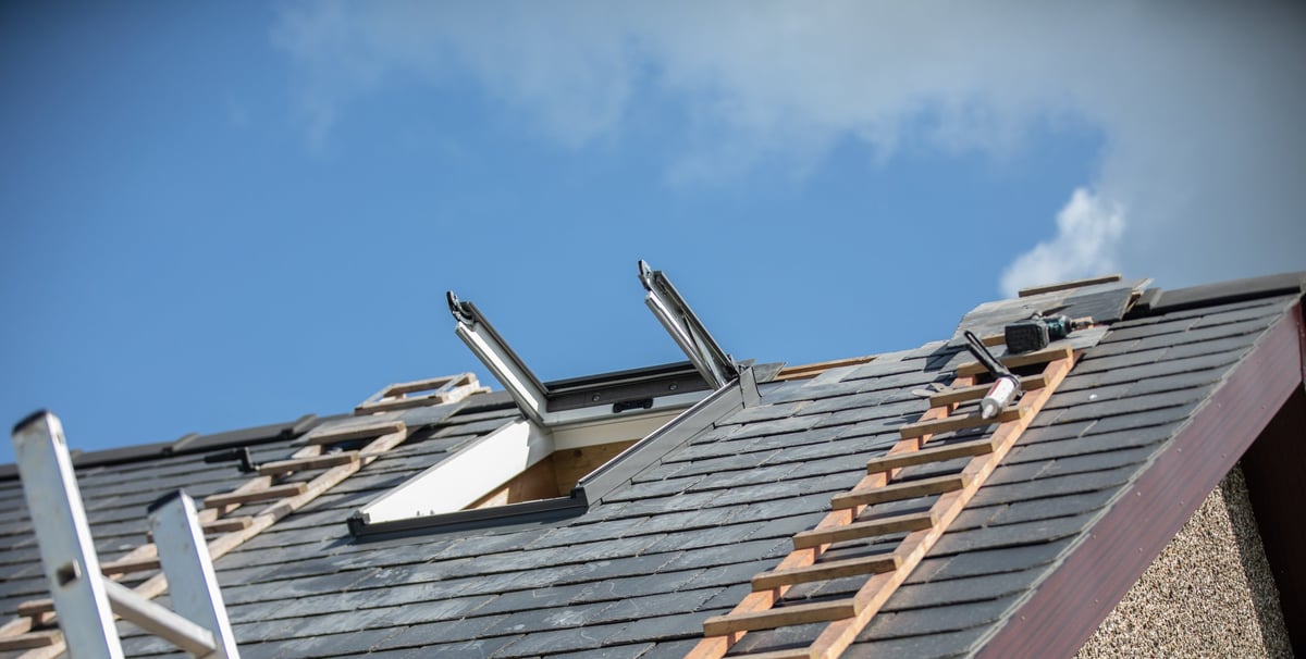 New loft room window being installed into a residential property with roof ladders - with blue skies