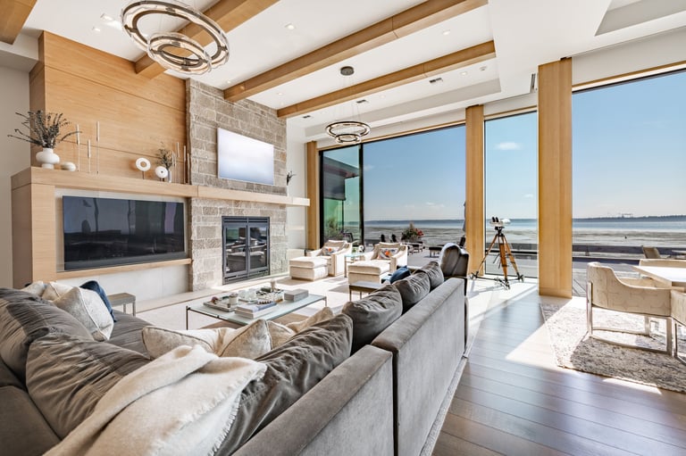 Luxurious living room interior with floor-to-ceiling aluminium sliding doors, elegant curtains, sectional sofa and breathtaking ocean and waterfront views