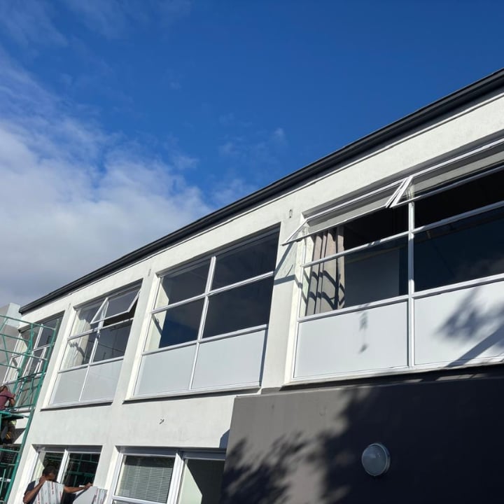 Modern two-story building with white and black exterior, large horizontal windows, and clear blue sky above