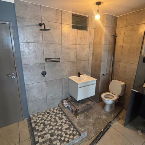 Modern bathroom with walk-in shower, white vanity, toilet, and checkered tile flooring