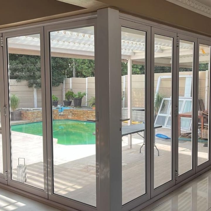 Large sliding glass doors opening to backyard with green swimming pool and patio furniture