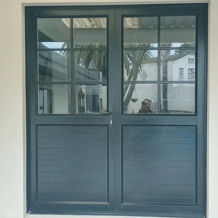 Teal blue double glass doors with horizontal paneled lower sections and multiple window panes, set in white wall
