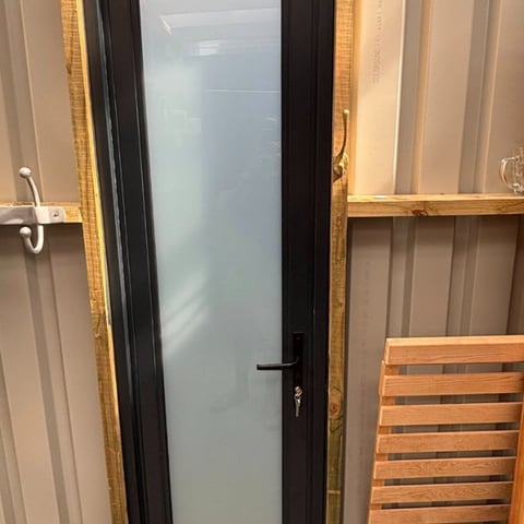 Black interior door with frosted glass panel in modern home setting with wooden frames and neutral walls