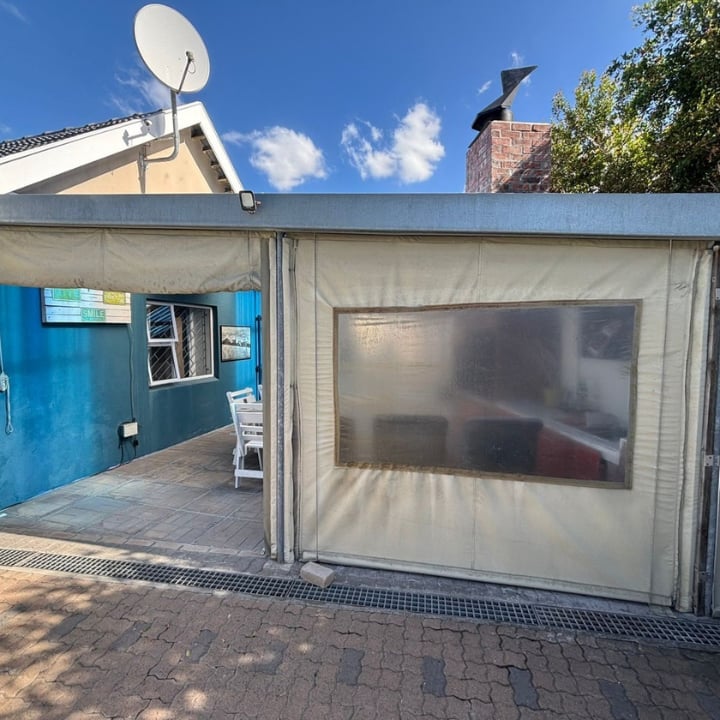 Small commercial kiosk with blue entrance door and gray storefront window under metal roof on brick paved ground