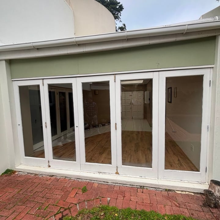 White multi-panel glass patio doors opening onto a brick patio from a house extension