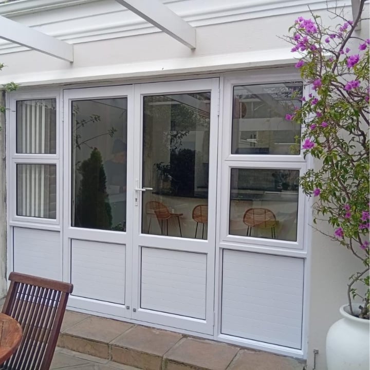 White glass patio doors with purple flowers climbing on the right side and wooden chair visible on the left
