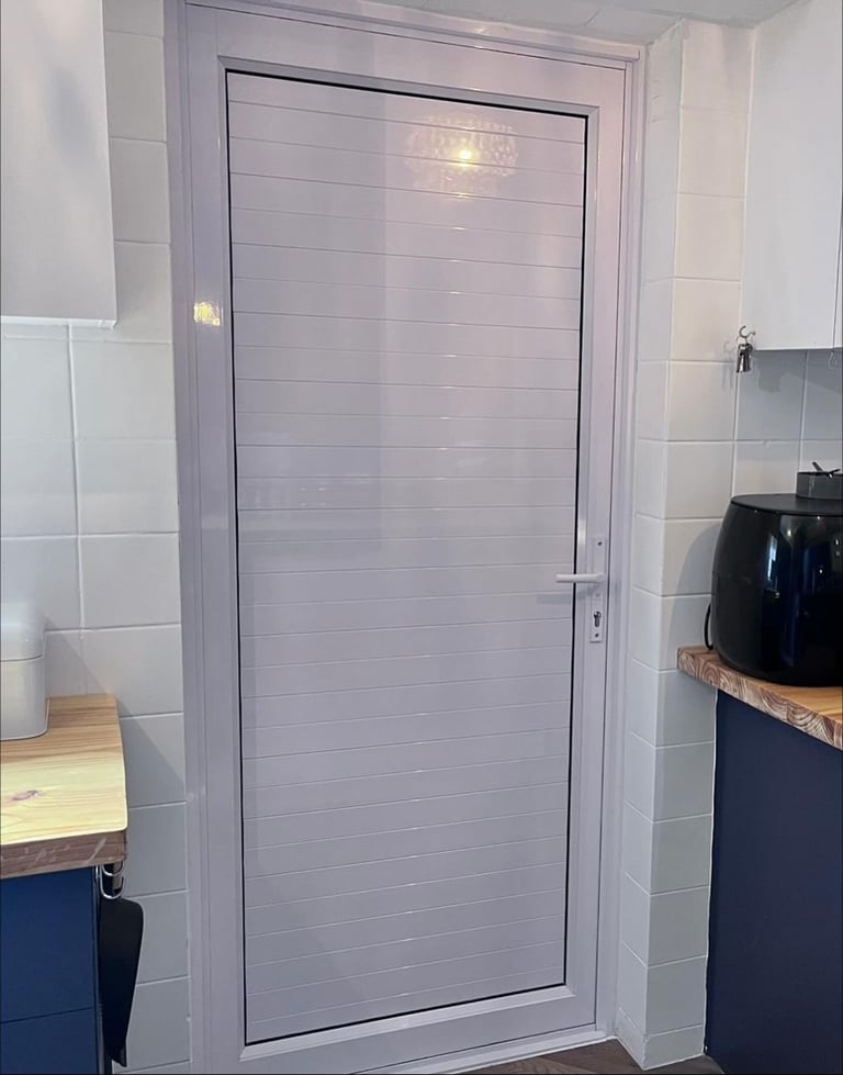 Modern frosted glass shower enclosure with gray frame in a tiled bathroom with dark blue vanity